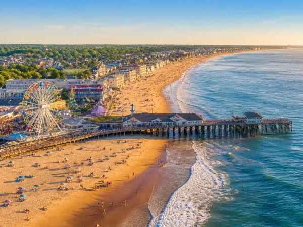 Aerial summer view of Old Orchard Beach Maine showing the sandy shoreline, Palace Playland Ferris wheel, and historic wooden pier extending into the Atlantic Ocean